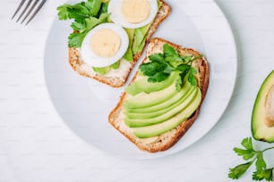 Toast mit Avocado und Ei auf weißem Teller. Draufsicht. Gesundes Frühstück