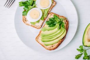 Toast with avocado and egg on white plate. Top view. Healthy breakfast