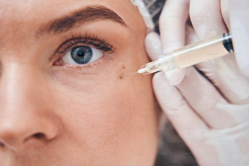 Professional cosmetologist using sterile syringe while doing anti-age face injection