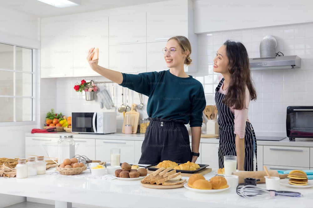 Due amiche si divertono mentre fanno colazione per un selfie in cucina.