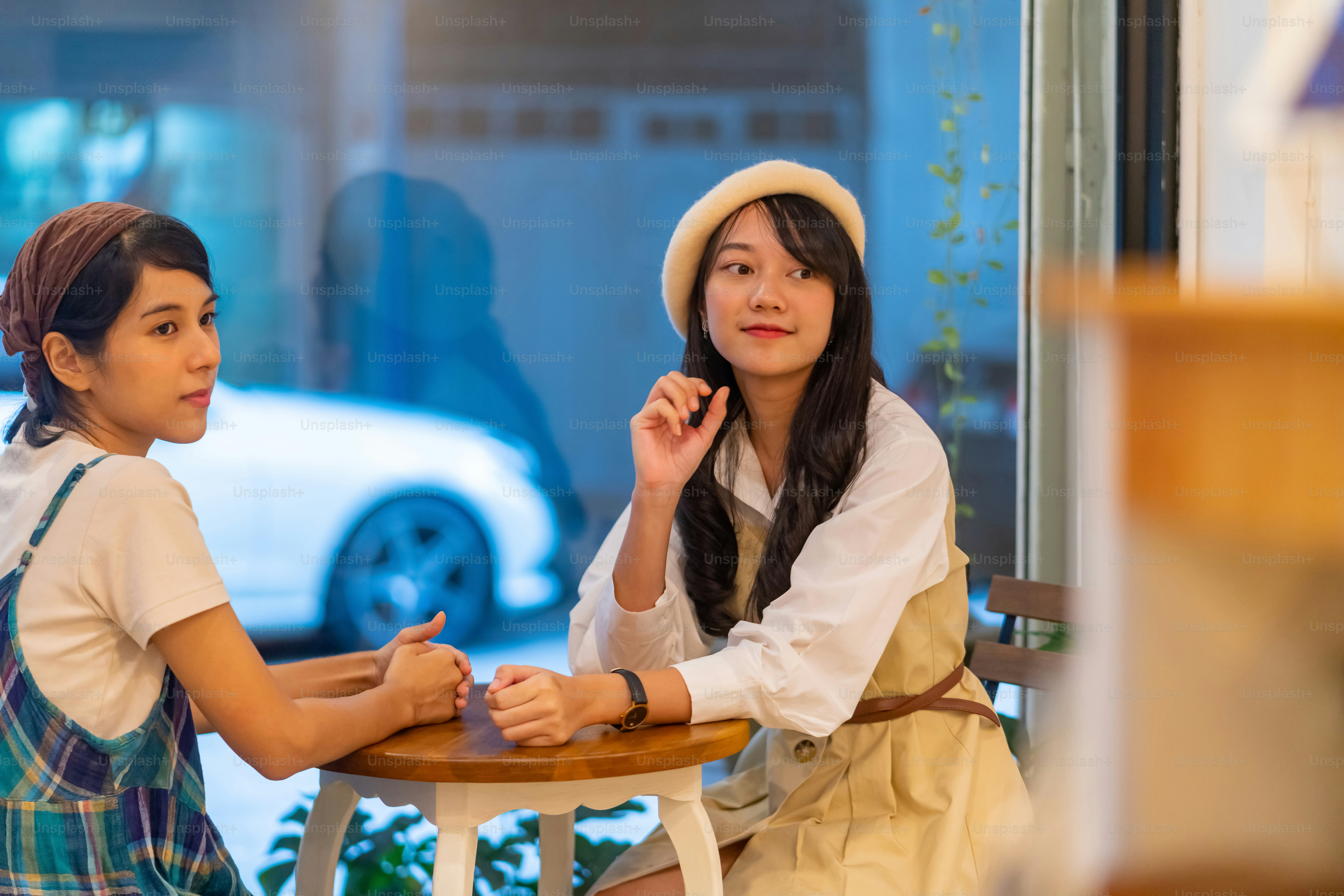 Young beautiful Asian woman friends sitting by the window in cafe with