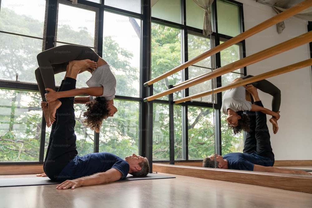 Una coppia sana e forte fa pratica di yoga e esercizi di allungamento del corpo insieme nello studio di fitness yoga. L'uomo e la donna del benessere si rilassano e si godono lo sport, l'allenamento, l'allenamento e lo stile di vita dell'attività indoor.
