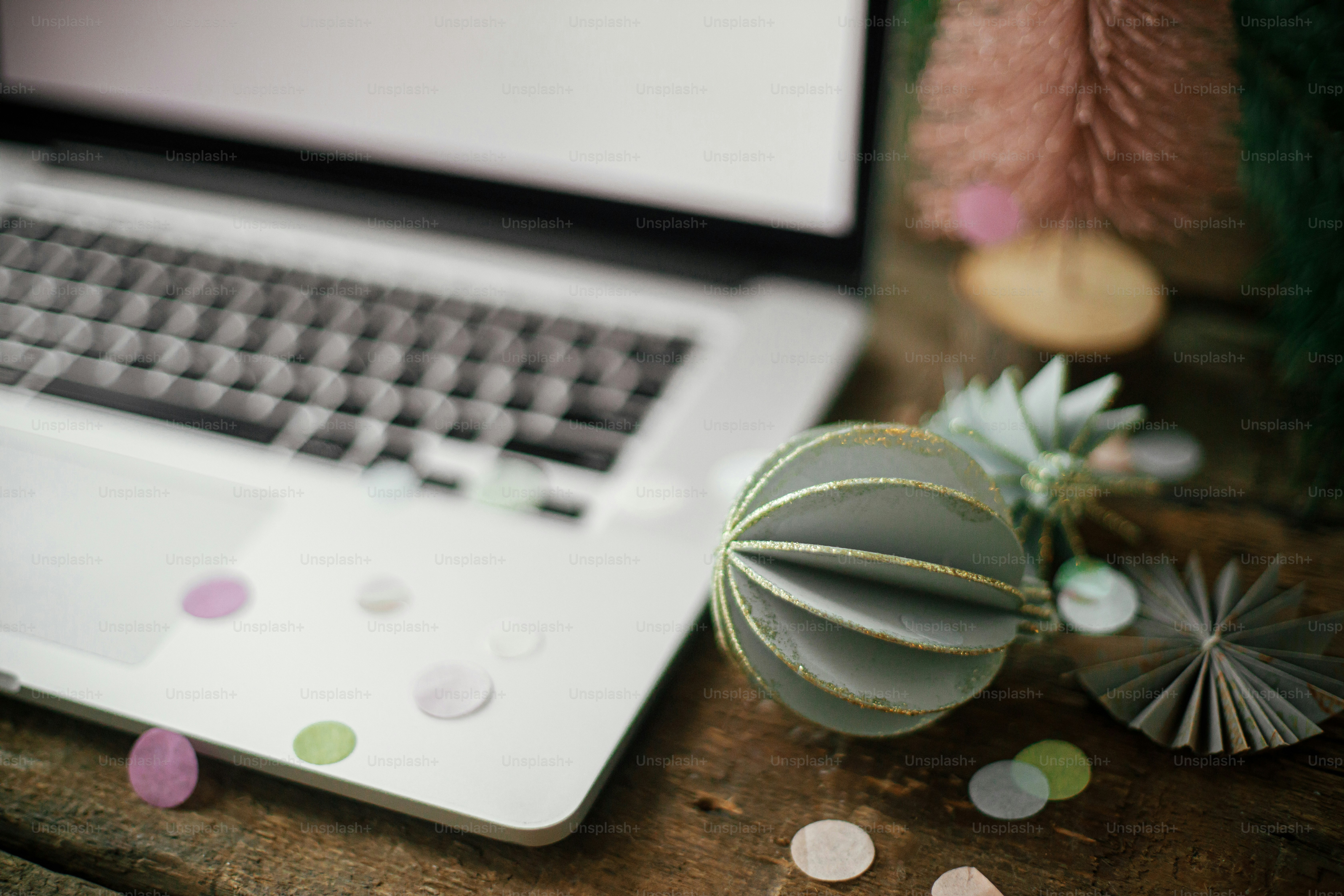 Stylish christmas ornaments and decorations on background of laptop with blank screen on rustic wooden table. Christmas Sales and shopping online. Remote work on holidays. Space for text