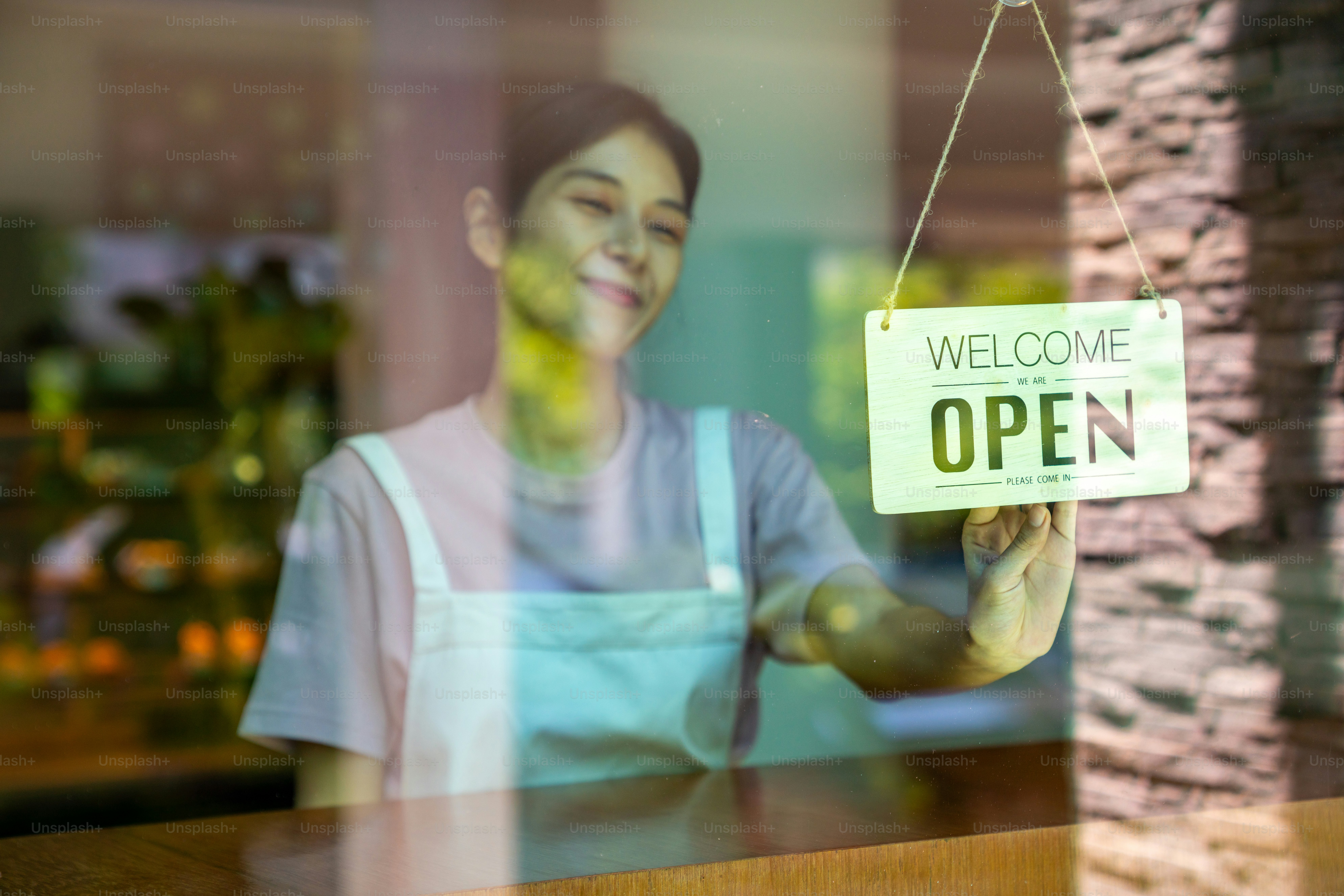 Femme asiatique barista de café marchant vers la porte du café et tournant le signe ouvert. Serveuse préparant le restaurant pour le service au client. Propriétaire d’une petite entreprise et concept de travail à temps partiel