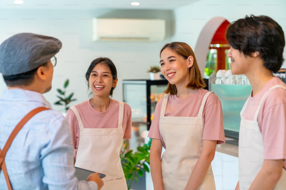 アジアの男性コーヒーショップのマネージャーは、作業前に男性と女性のスタッフチームにブリーフィングします。スモールビジネスカフェやレストランのオーナーが、オープン前にアルバイト社員に接客準備を指導