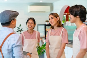 Il manager della caffetteria maschio asiatico che informa il team del personale maschile e femminile prima di lavorare. Il proprietario di un bar e di un ristorante di piccole imprese istruisce un dipendente part-time che prepara il servizio ai clienti prima dell'apertura