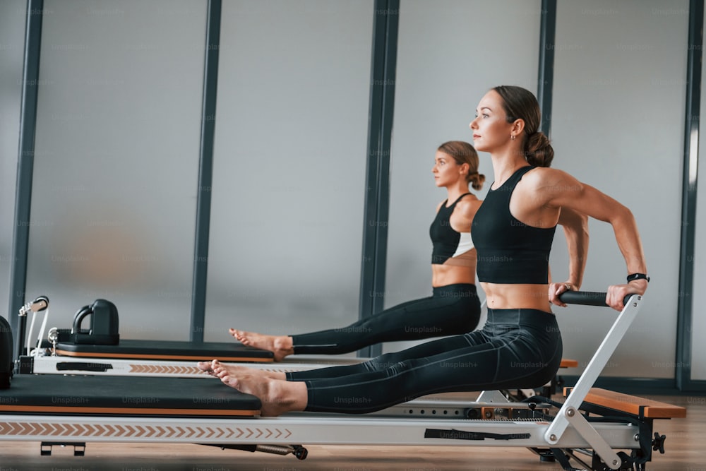 Hände Kraft. Zwei Frauen in sportlicher Kleidung und mit schlankem Körper haben gemeinsam einen Fitness-Yoga-Tag drinnen.