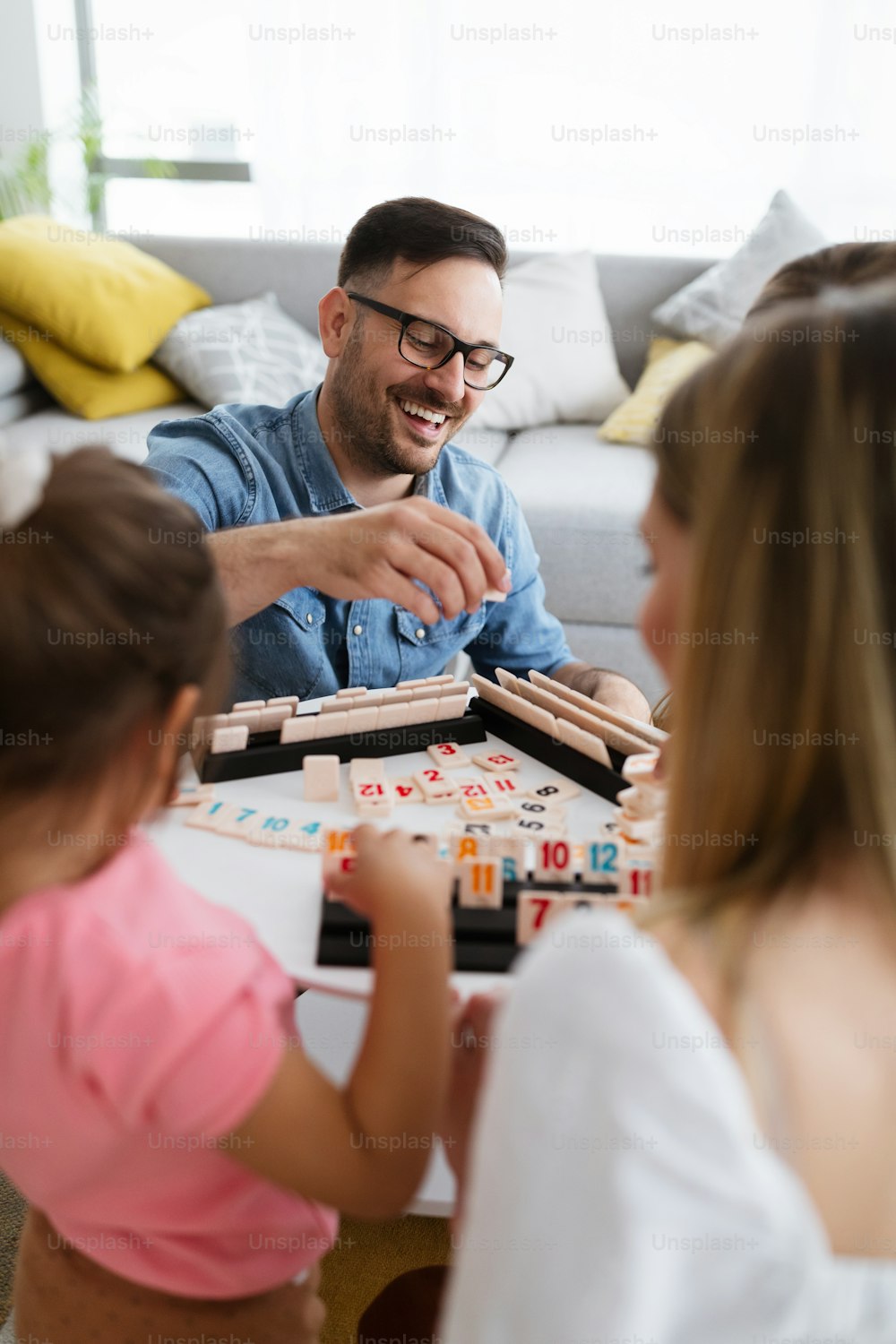 Happy parents and children having fun, playing board game at home