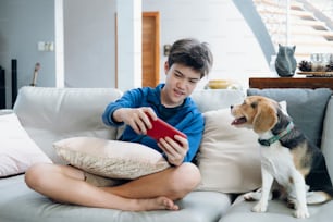 The boy playing game online on smartphone at home.