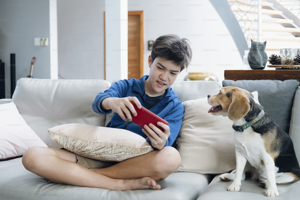 The boy playing game online on smartphone at home.