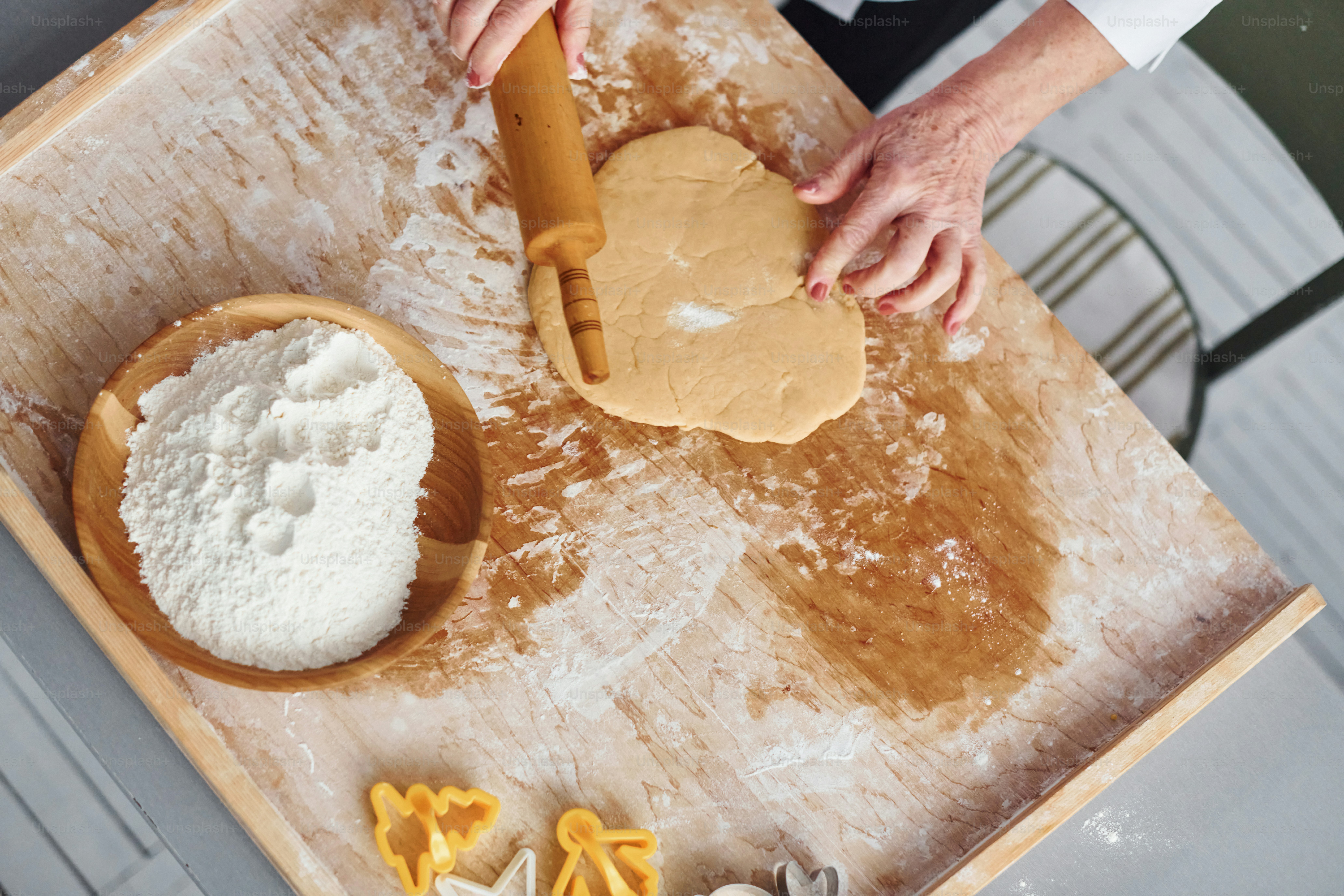 Une femme âgée cuisine des biscuits de Noël dans la cuisine pendant la journée