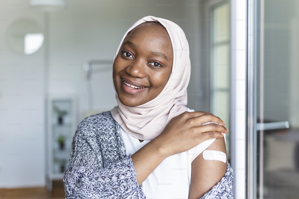 Vendaje adhesivo en el brazo después de la inyección, vacuna o medicamento,VENDAJES ADHESIVOS YESO - Equipo médico,Enfoque suave Vendaje adhesivo en una mujer africana musulmana braquio después de la vacunación covid-19