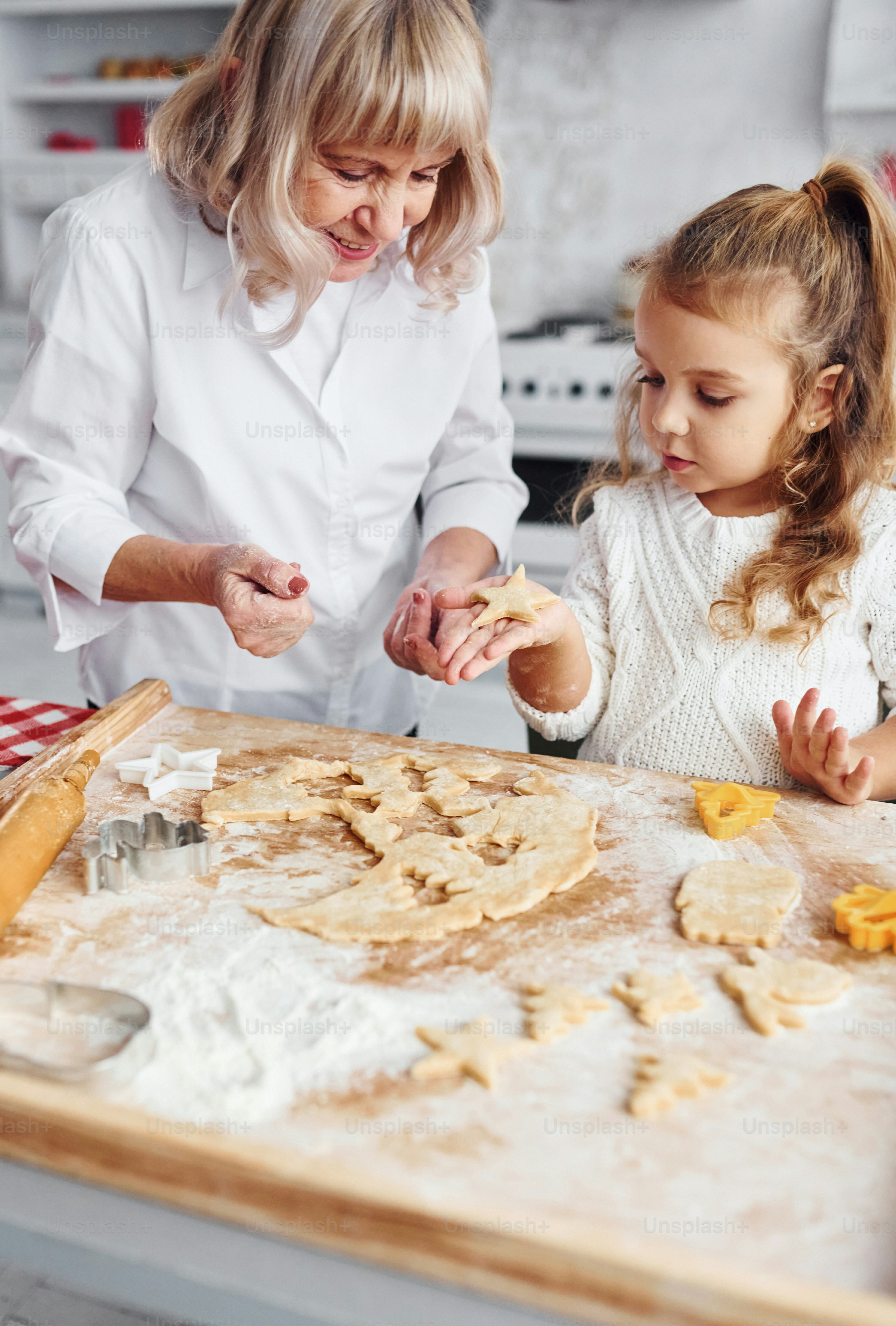 Processus d’enseignement. Une grand-mère âgée avec sa petite-fille cuisine des bonbons pour Noël dans la cuisine