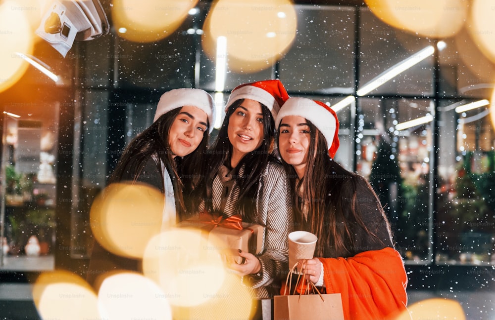 Três mulheres alegres passam as férias de Natal juntas ao ar livre. Concepção de ano novo.