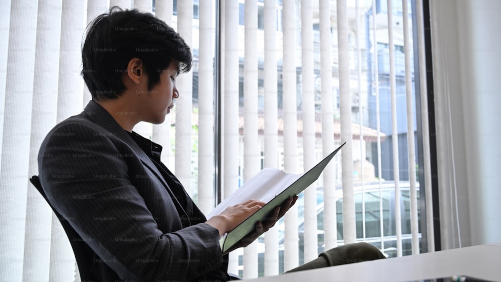 Successful businessman reading business document at office.