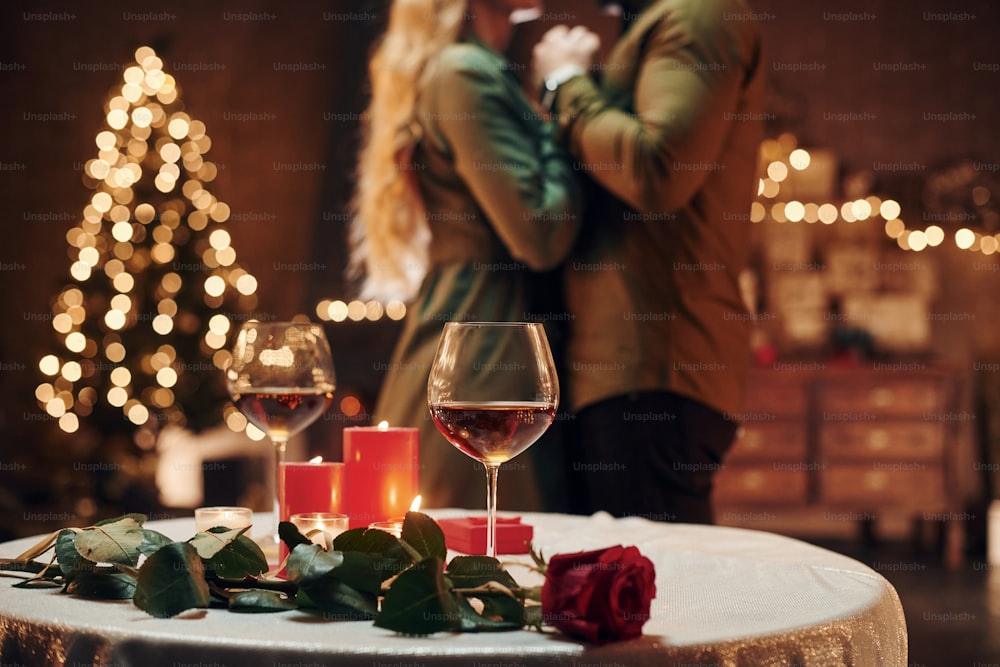 De pie y bailando. Una joven y encantadora pareja tiene una cena romántica juntos en el interior.