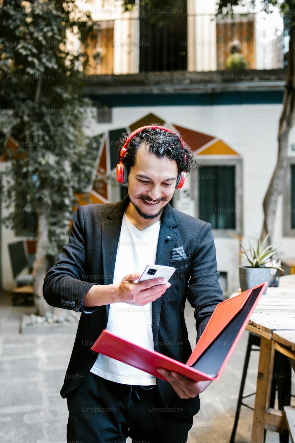 latin man working in a creative office with smartphone and headphones in Mexico city