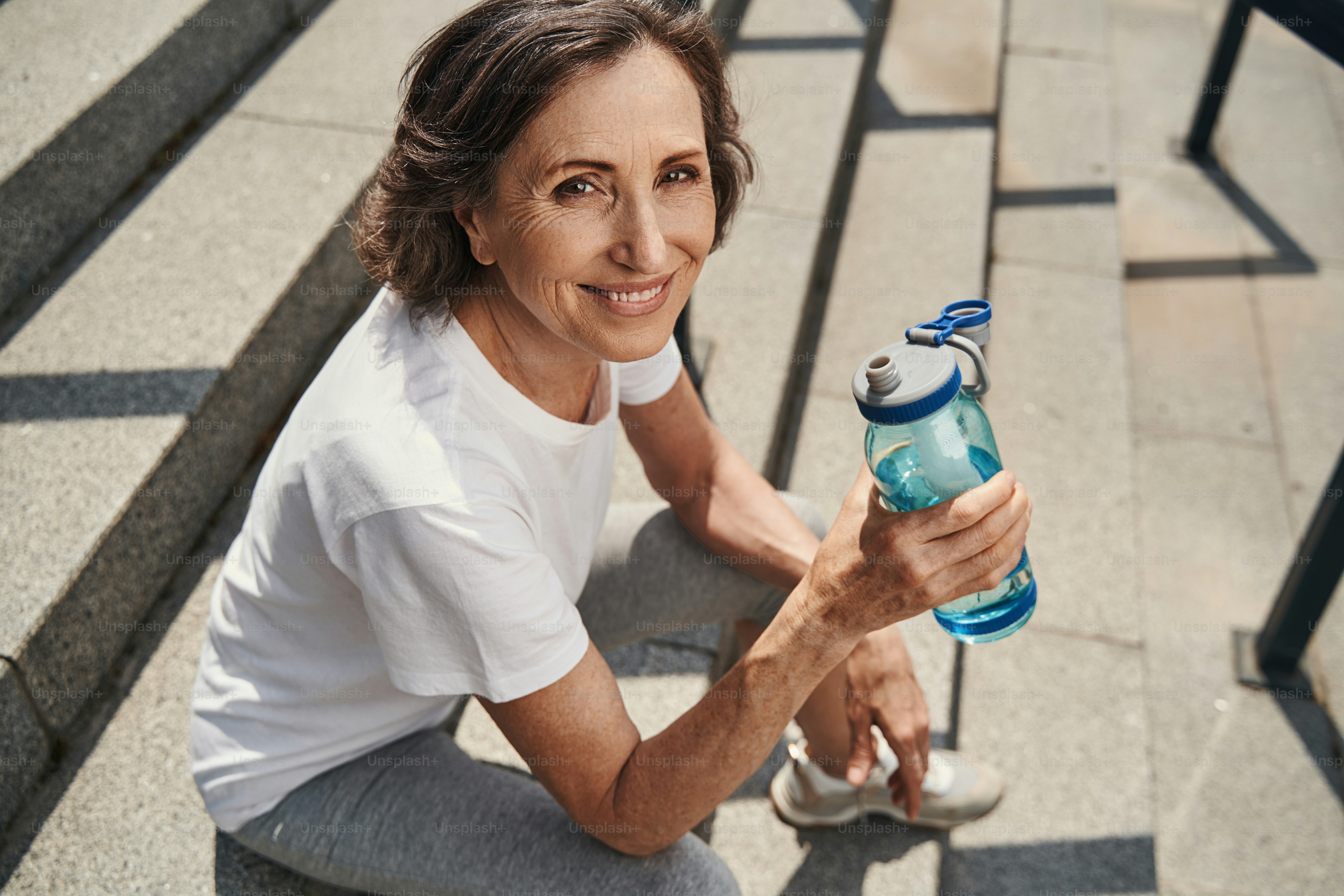 Top view waist up portrait of joyful beautiful sporty woman sitting on