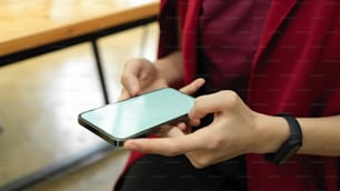 Cropped shot, businesswoman using smartphone to tell her assistant for the next meeting, phone in hands, phone blank screen