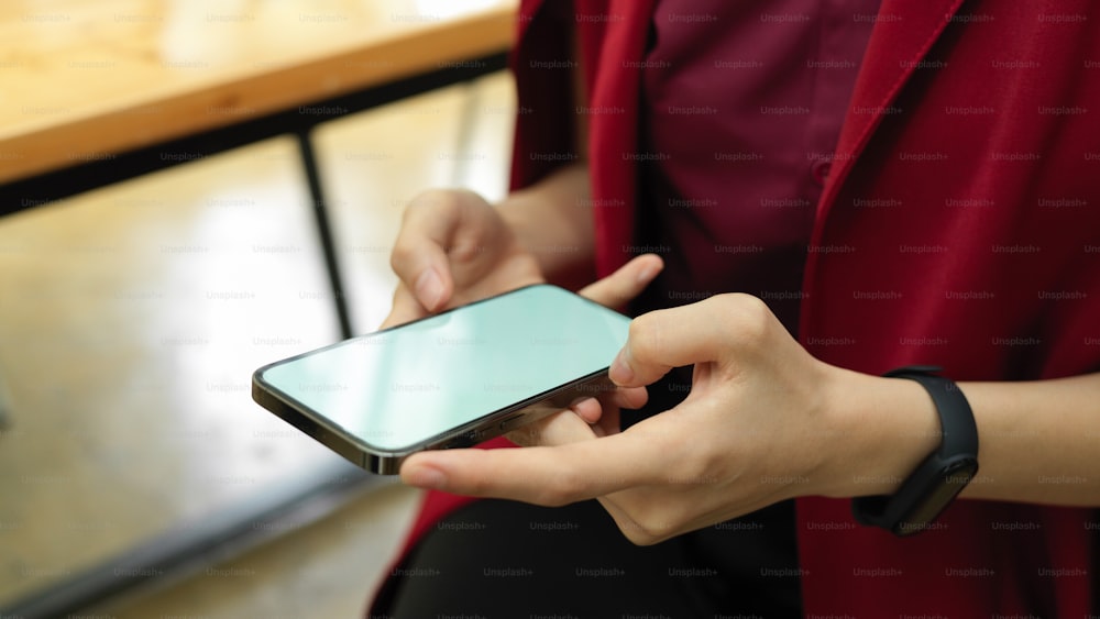 Cropped shot, businesswoman using smartphone to tell her assistant for the next meeting, phone in hands, phone blank screen