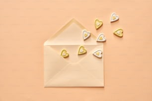 Kleine Herzen, die aus einem Umschlag fliegen - Liebe oder Valentinstag-Konzept auf pastellfarbenem Hintergrund