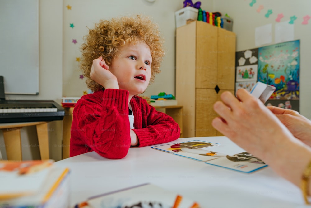 Boy on the session of speech therapist. Lesson on the development of speech in kindergarten. Teacher spreads out puzzle in front of the child.