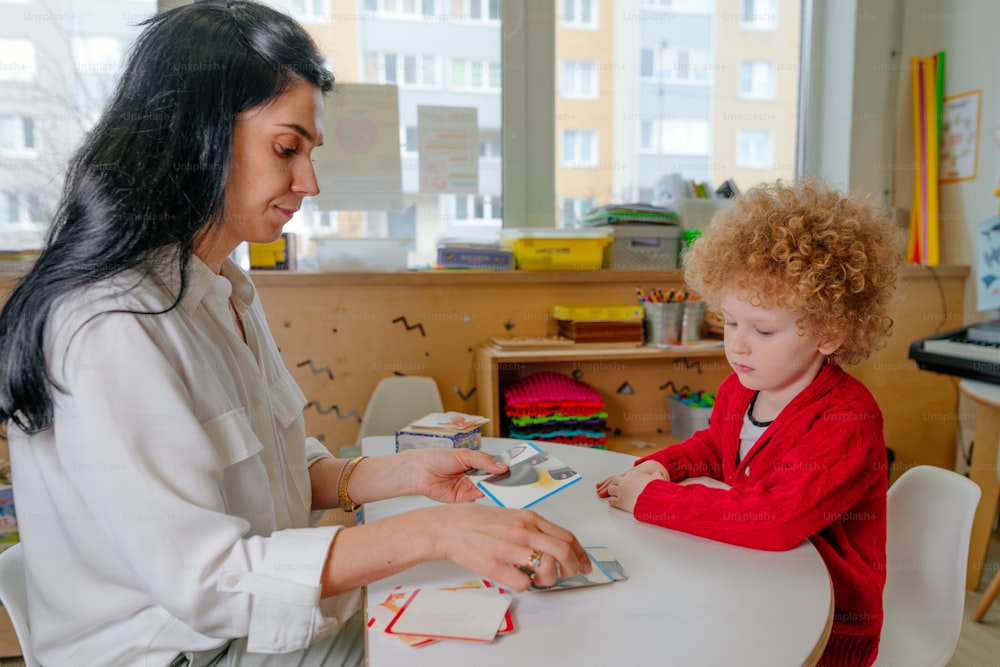 Boy on the session of speech therapist. Lesson on the development of speech in kindergarten. Teacher spreads out puzzle in front of the child.