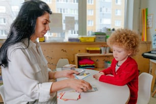 Boy on the session of speech therapist. Lesson on the development of speech in kindergarten. Teacher spreads out puzzle in front of the child.