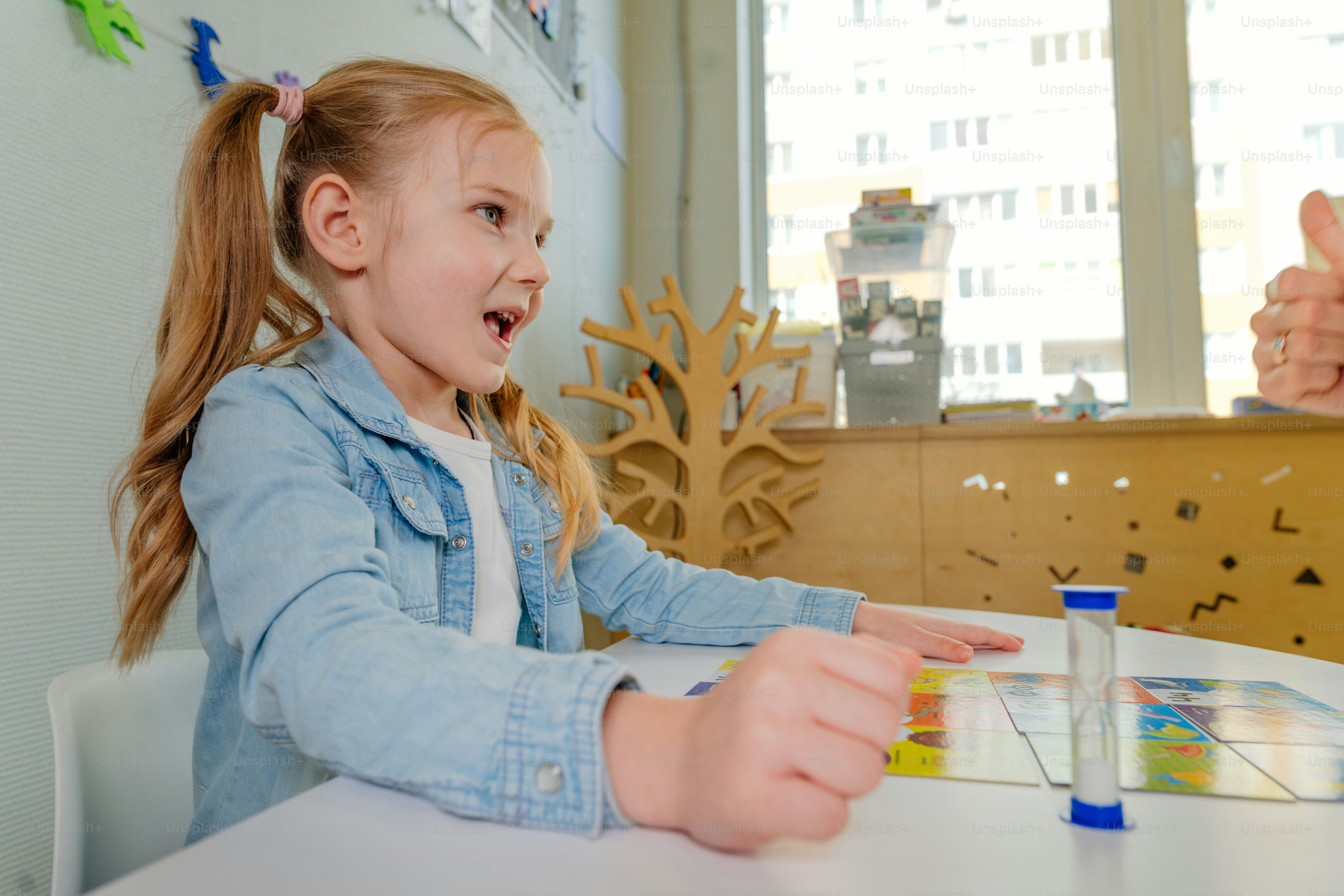 Niña en la sesión de logopeda. Lección sobre el desarrollo del habla en el jardín de infantes. La maestra extiende el rompecabezas frente al niño.