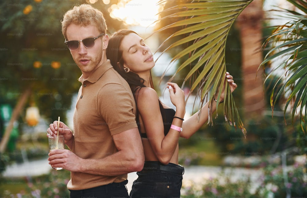 Man in sunglasses, woman in black bra. Happy young couple is together on their vacation. Outdoors at sunny daytime.