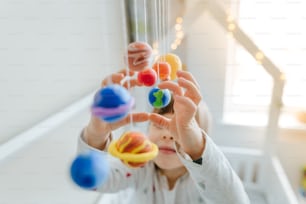 Solar system model hanging over the kid bed. DIY activity for children concept. Selective focus.