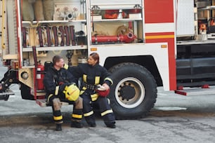 Male and female firefighters in protective uniform is outdoors together.