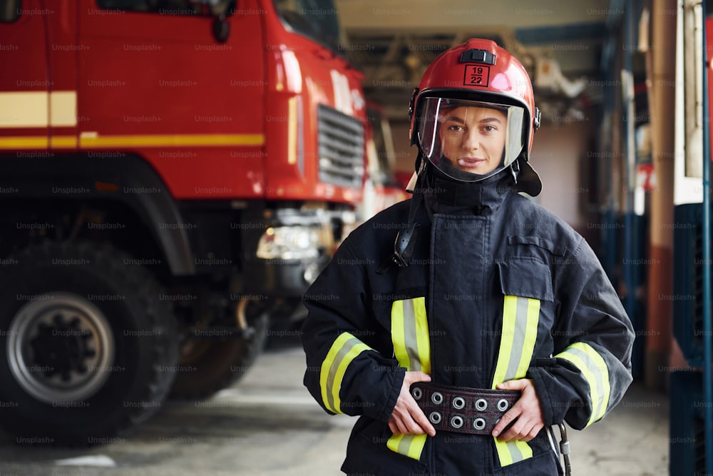 Female firefighter in protective uniform standing near truck.