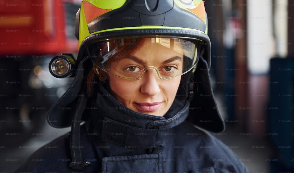 Close up view. Female firefighter in protective uniform standing near truck.