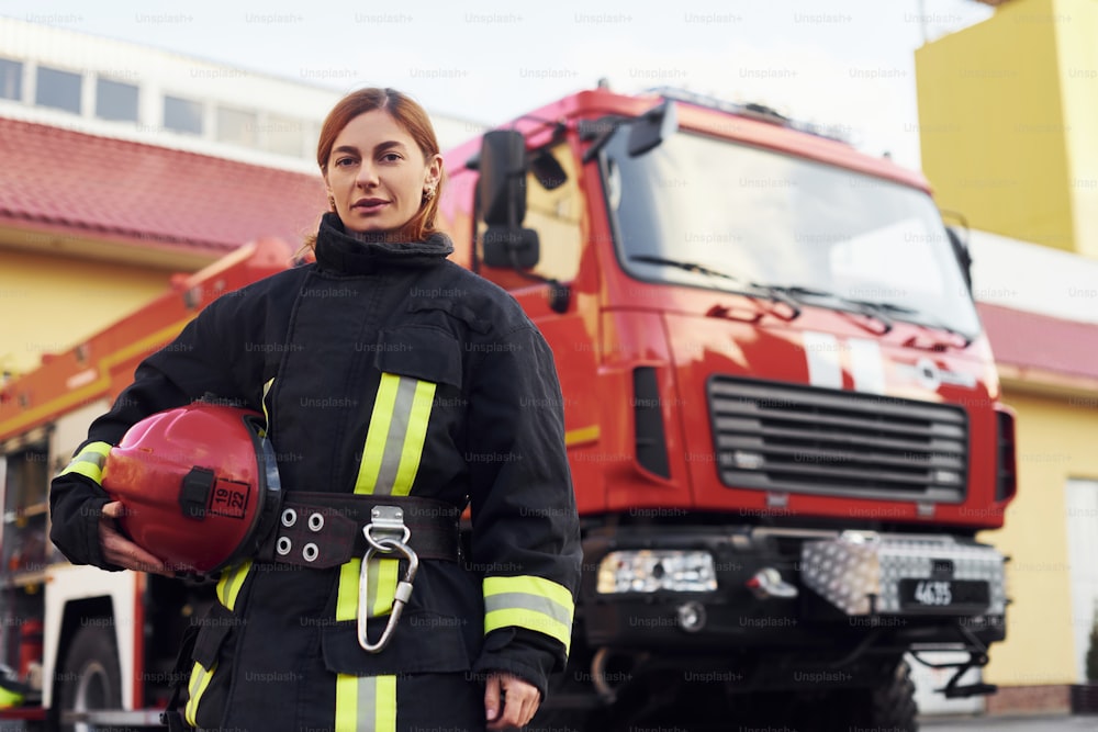 Female firefighter in protective uniform standing near truck.