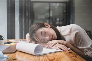 Tired young business woman sleeping at her office desk.