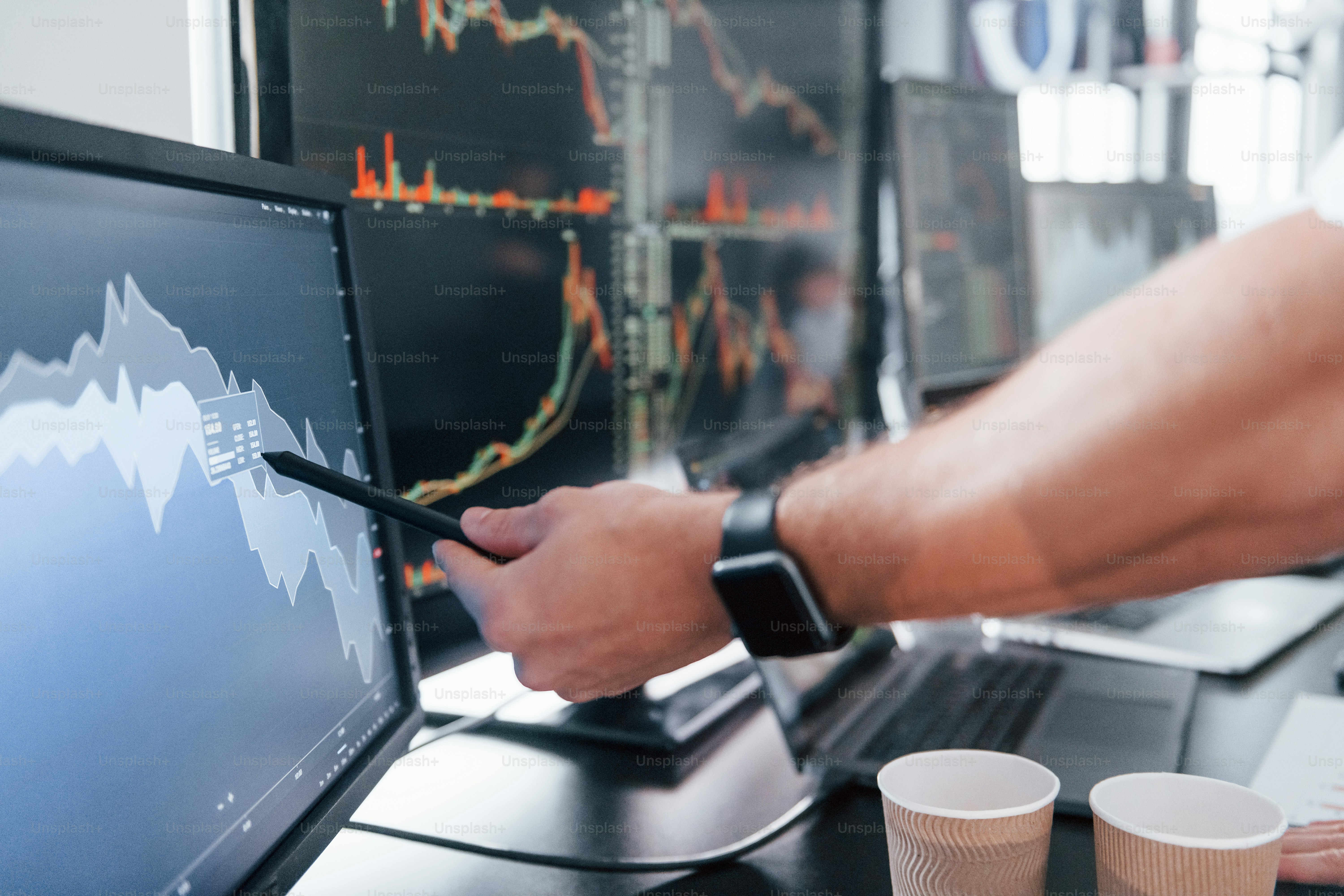 Close up view of man's hand that points at part of stock graph on display.