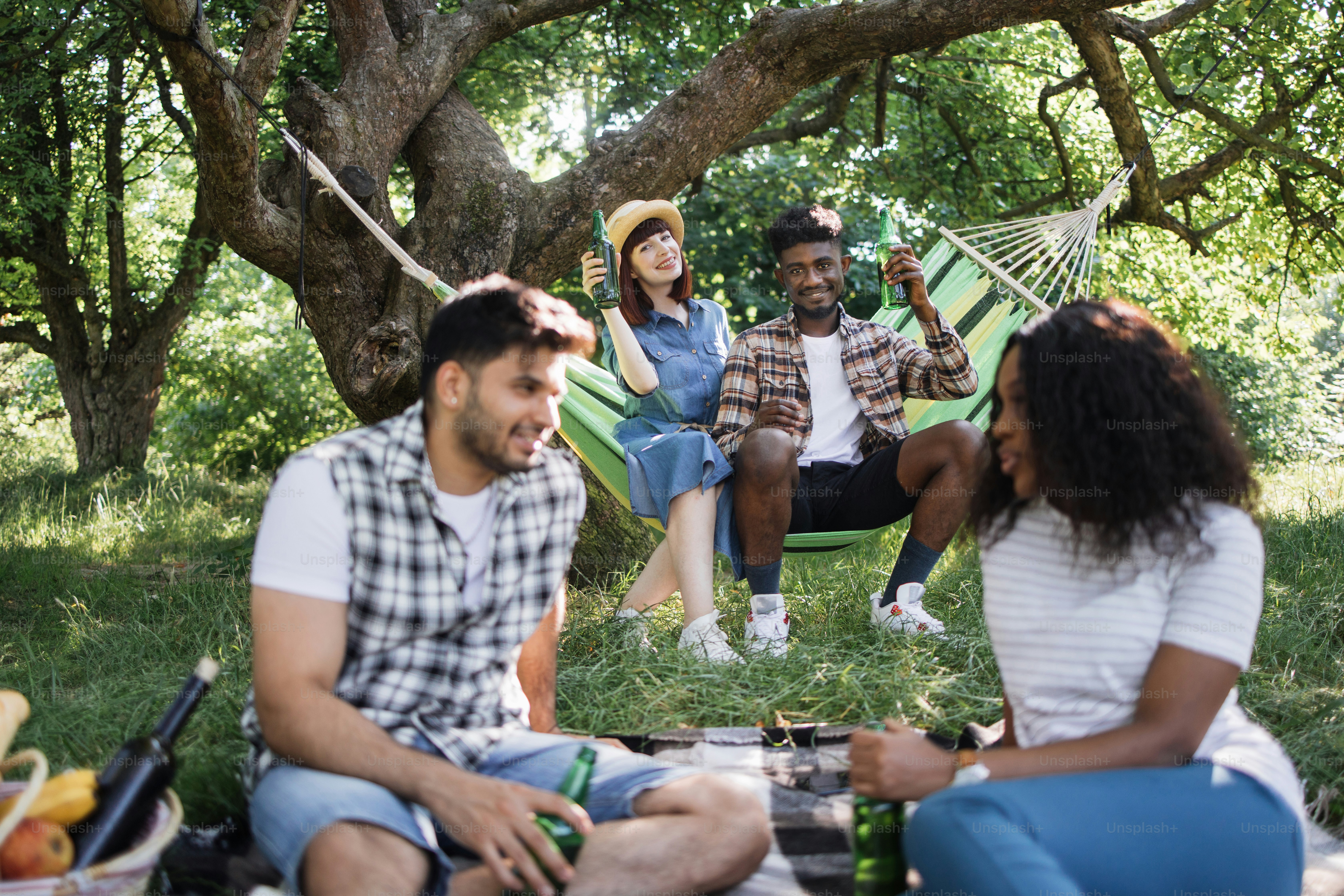 Group of four multicultural friends gathering around barbeque for ...