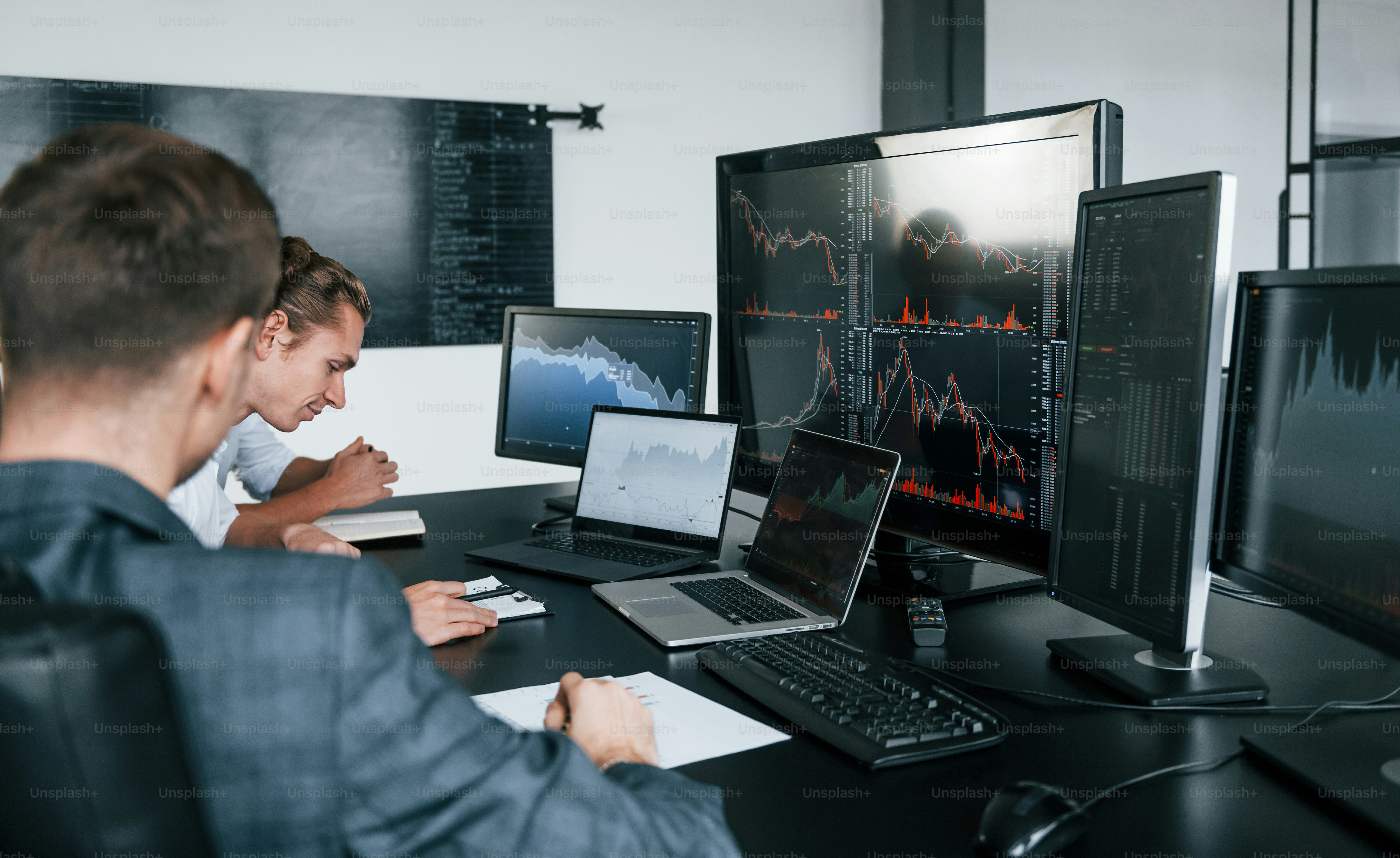 Conception of teamwork. Team of stockbrokers works in modern office with many display screens.