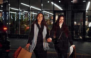 Walks with packages. Just from shopping. Happy sisters twins spends Christmas holidays together outdoors. Conception of new year.