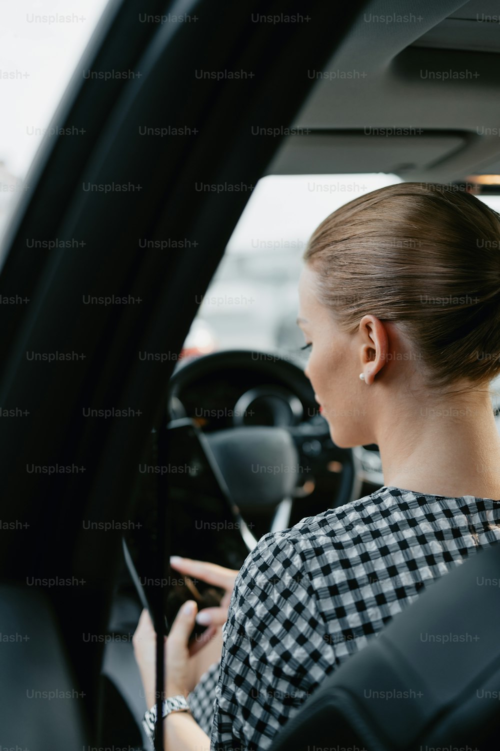 Beautiful young woman working as used car seller. She is using digital tablet and checking car condition before customer or buyer. Used vehicle dealership.