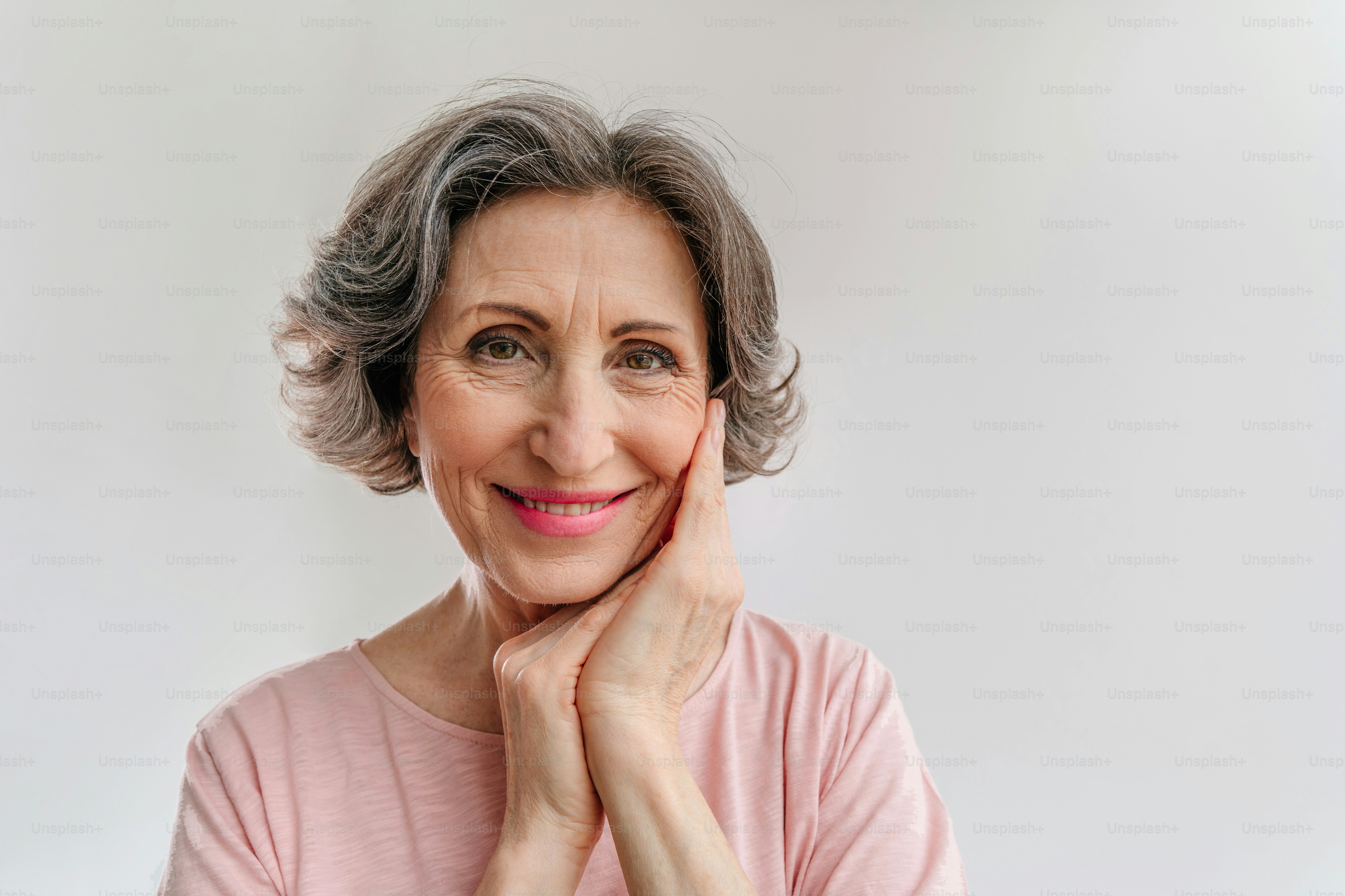 Retrato de una mujer madura feliz y elegante sobre fondo gris claro con espacio en blanco para texto.