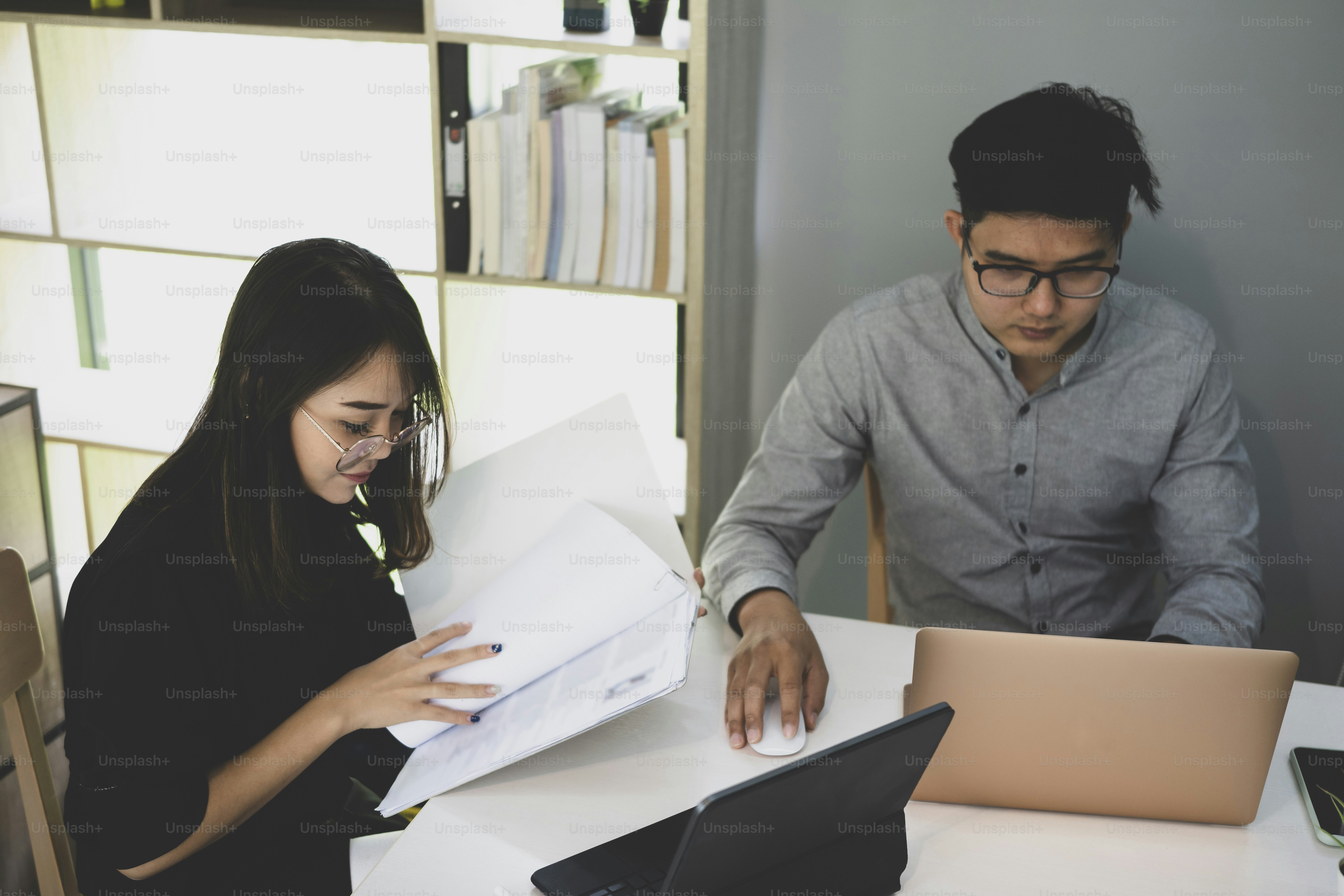 Two businesspeople analyzing financial documents together in meeting room.