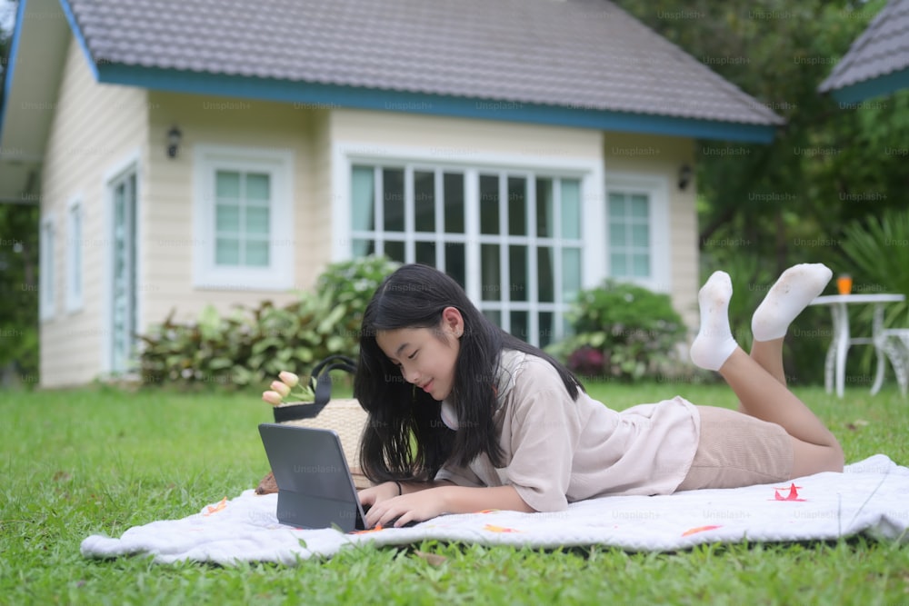 Young woman laying on a blanket and using computer tablet.