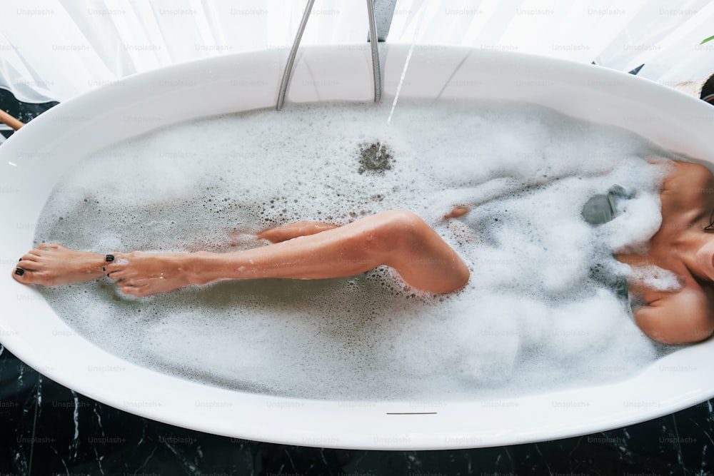 Particle view of legs. Beautiful young woman have free time at home in the bath.