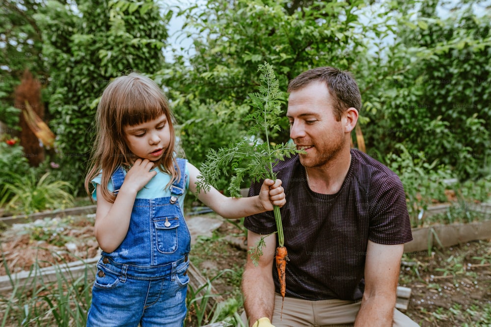 Kleine Tochter hilft ihrem Vater auf dem Bauernhof. Outdoor-Aktivitäten für Familien.
