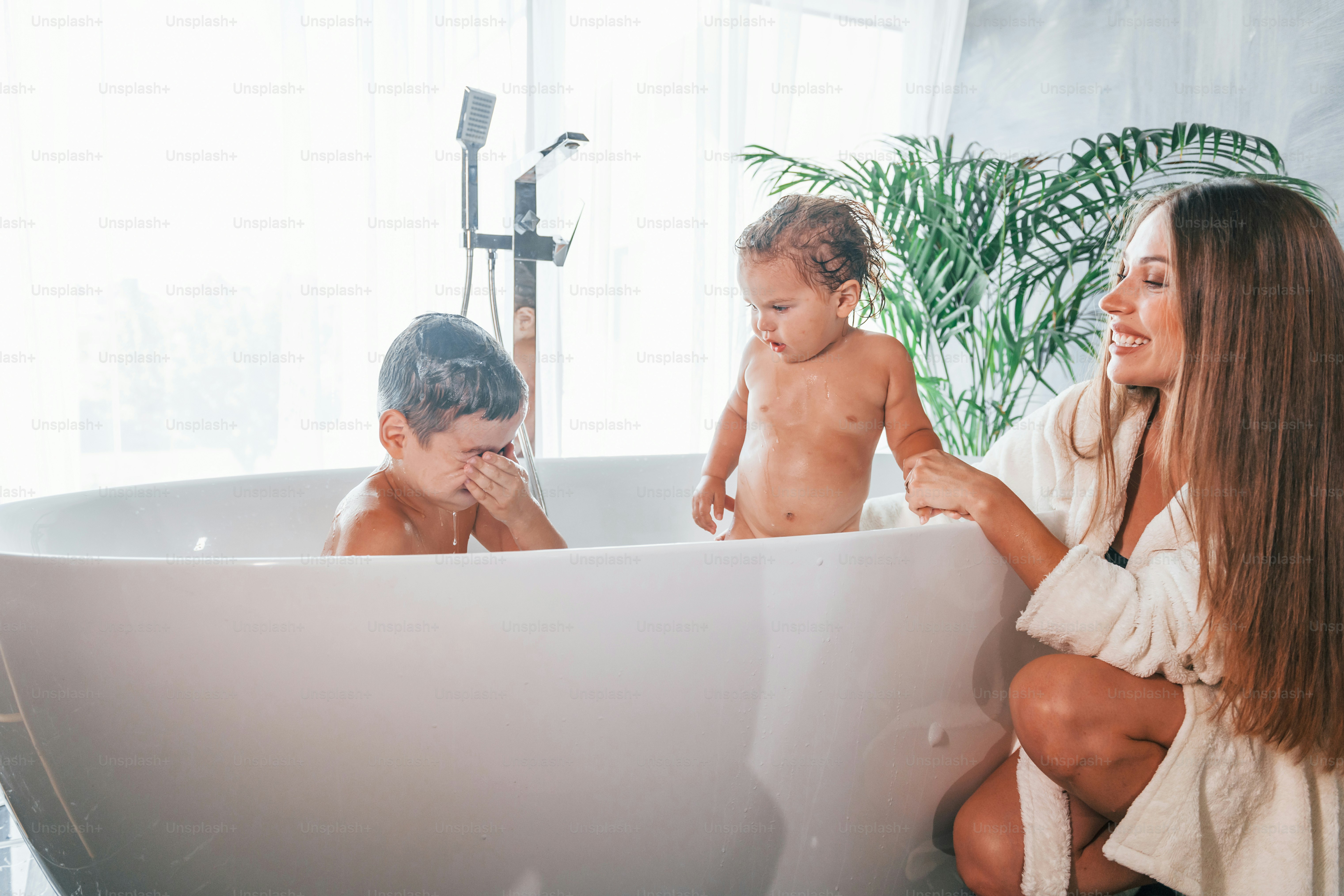 After washing. Young mother helps her son and daughter.