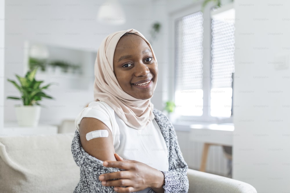 Vendaje adhesivo en el brazo después de la inyección, vacuna o medicamento,VENDAJES ADHESIVOS YESO - Equipo médico,Enfoque suave Vendaje adhesivo en una mujer africana musulmana braquio después de la vacunación covid-19