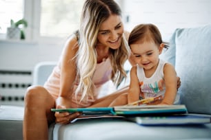 Eine junge Mutter bringt ihrem kleinen Mädchen das Lesen bei.
