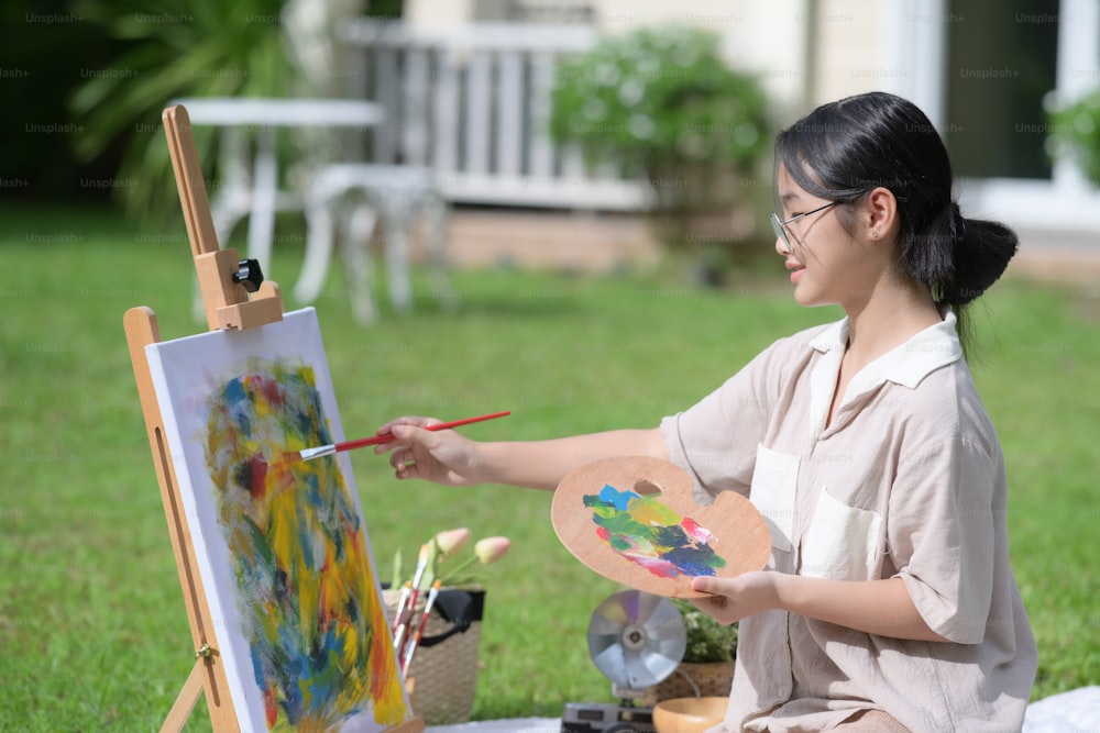 Asian girl having fun painting on easel at outdoor.